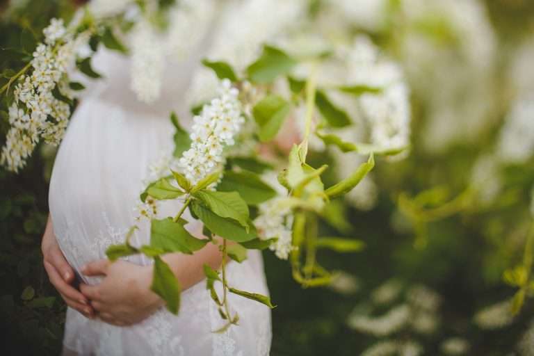 massage femmes enceintes au milieu de lilas en robe blanche